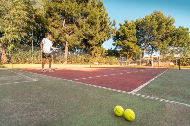 Uomo che gioca a tennis su un campo all'aperto.