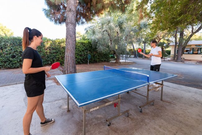 Due persone giocano a ping pong all'aperto.