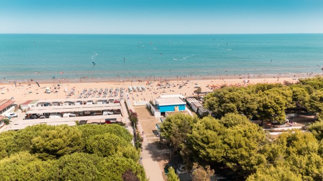 Spiaggia sabbiosa con ombrelloni e lettini.