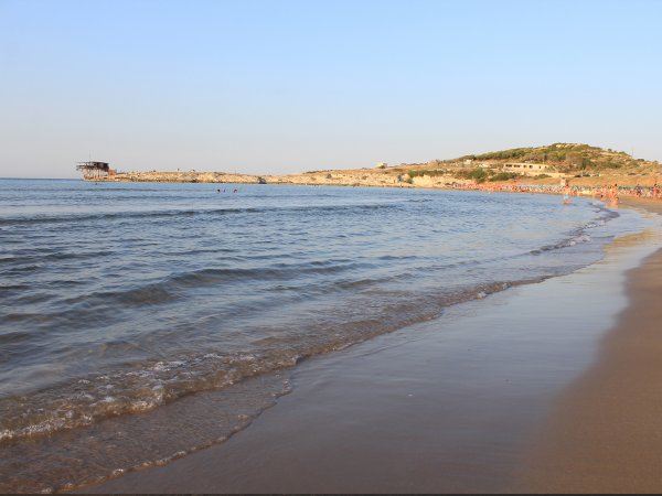 Una spiaggia con onde leggere che lambiscono la riva, vista di una costa lontana.