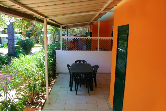 Patio coperto con tavolo e sedie, parete arancione.