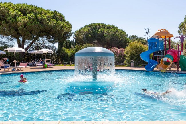 Una piscina con giochi acquatici e una fontana centrale.