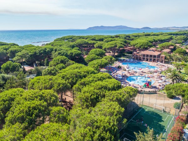 Vista aerea di un resort con piscine, tra pini e vicino al mare.