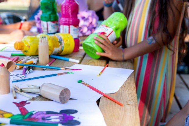 Materiali da disegno e colori su un tavolo con mani di bambini.