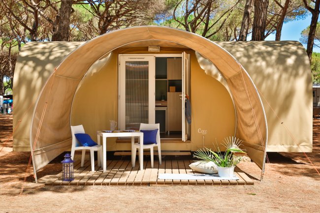 Una tenda moderna con veranda, tavolo, sedie e decorazioni all'esterno.
