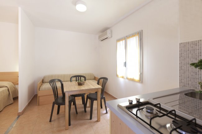 Tavolo con sedie vicino a finestra, cucina e divano accanto.