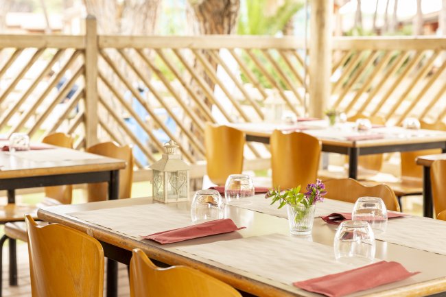 Tavola apparecchiata con bicchieri e fiori in un ristorante all'aperto.