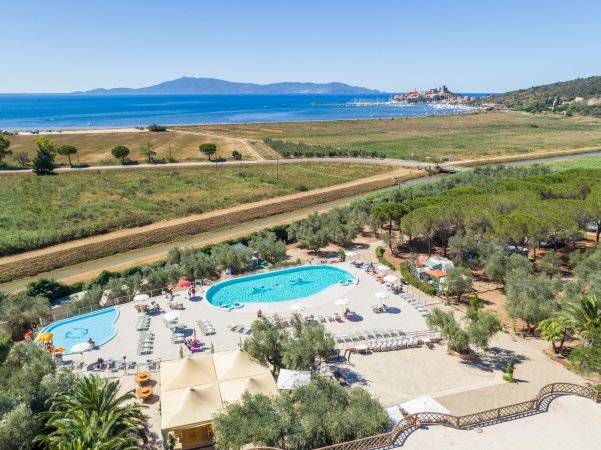 Piscine in un'area aperta, vista sul mare e una collinetta in lontananza.