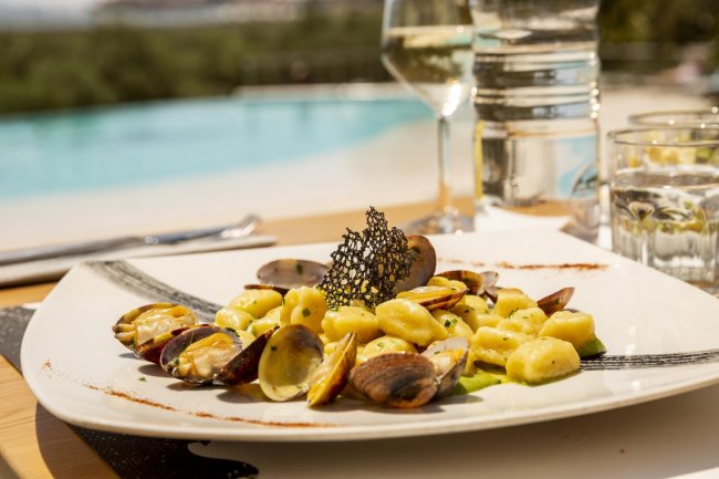 Piatto di gnocchi con vongole, servito vicino a una piscina.
