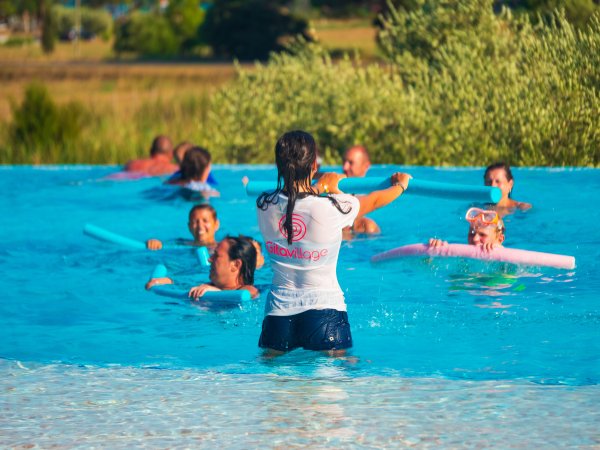 Lezione di nuoto in piscina con istruttrice e partecipanti.