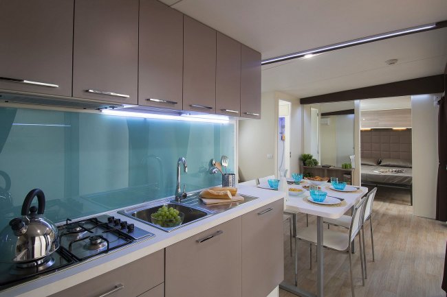 Cucina moderna con tavolo apparecchiato, vista su una camera.