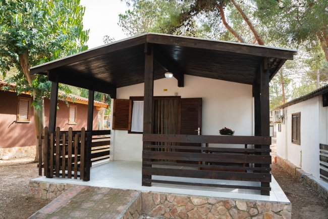 Un bungalow marrone con veranda coperta.