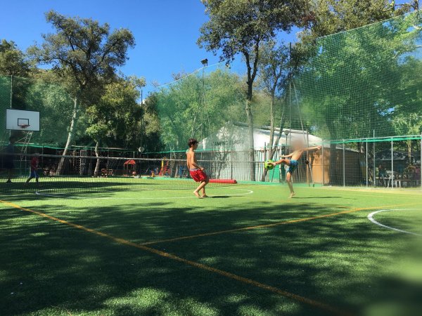 Campo sportivo all'aperto con reti e due persone che giocano.
