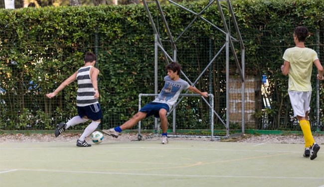 Tre ragazzi giocano a calcio su un campo all'aperto.