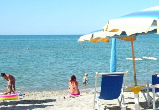 Spiaggia con ombrelloni colorati, sedie a sdraio e persone che si rilassano vicino al mare.