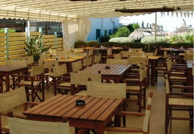 Terrazza coperta con tavoli e sedie in legno, vista verso l'esterno.
