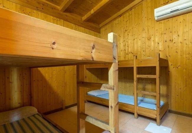 Una camera in legno con letti a castello e aria condizionata.