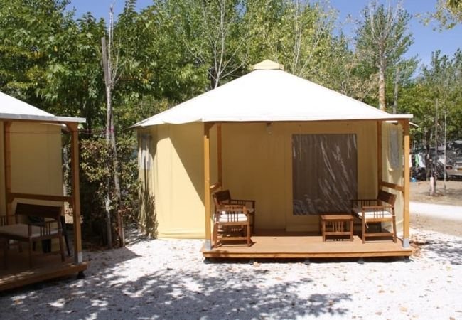 Una tenda glamping con veranda, mobili da esterno e tetto bianco.