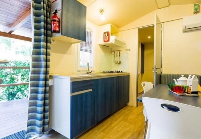 Interno di una casa mobile con cucina compatta, tavolo e sedie.
