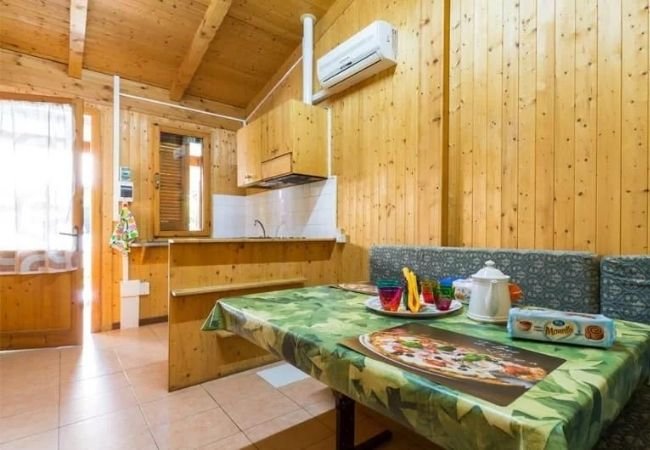 Interno in legno con tavolo apparecchiato, cucina e condizionatore.