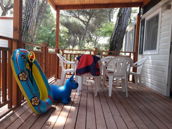 Veranda in legno con tavolo e sedie di plastica.