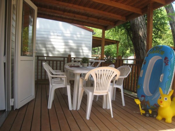 Veranda in legno con tavolo bianco e canotto.