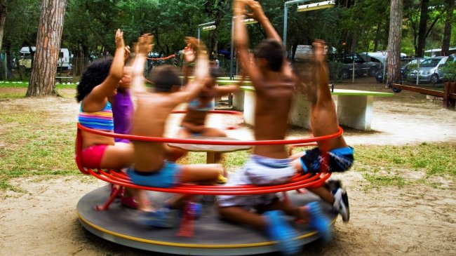 Bambini su giostra rossa in un parco giochi.