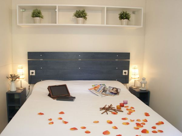 Camera matrimoniale con petali di rosa sul letto, luci soffuse e decorazioni delicate.