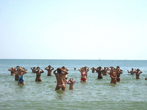 Gruppo di persone in acqua che sembrano fare esercizi sotto il sole.