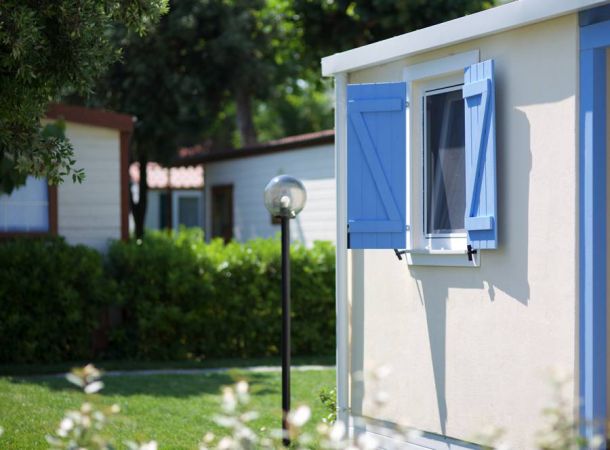 Una casa mobile con persiane blu aperte e un prato verde.