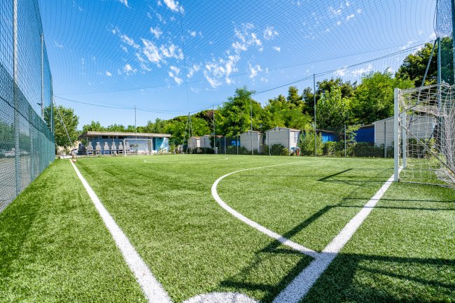 Campo da calcio recintato con cielo sereno sopra.