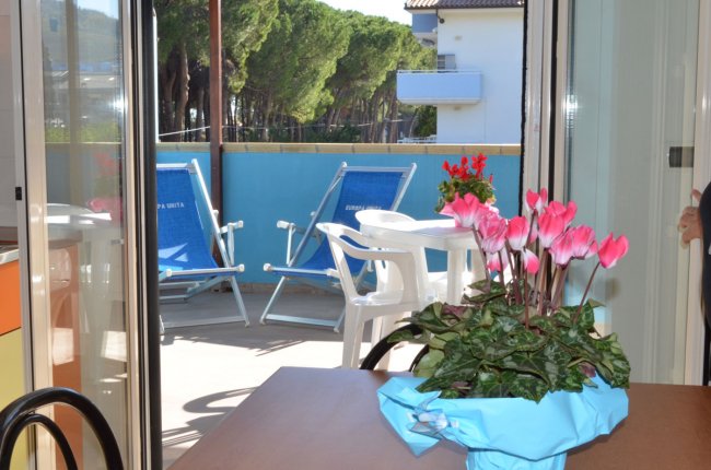 Terrazza con sedie a sdraio blu e un tavolo con fiori rosa.