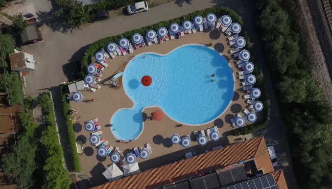 Vista aerea di una piscina con ombrelloni allineati lungo il perimetro.