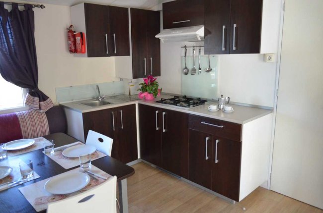Cucina moderna con mobili scuri, piano cottura, lavello e tavolo da pranzo apparecchiato.