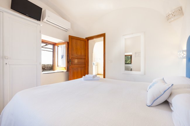 Stanza con letto, porta aperta e finestra soleggiata.