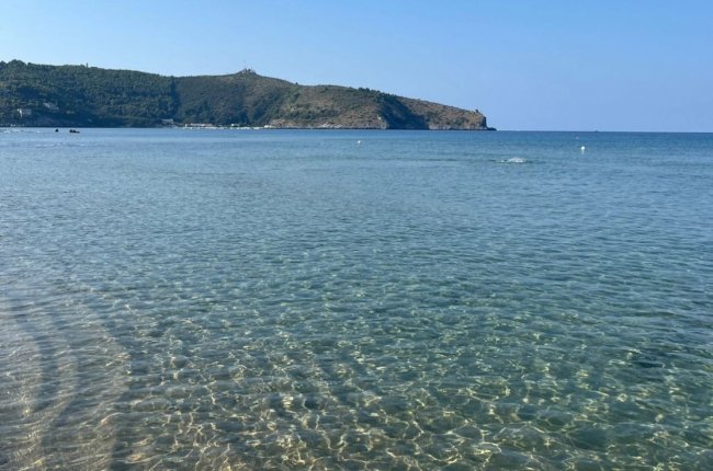 Mare cristallino con colline in lontananza.