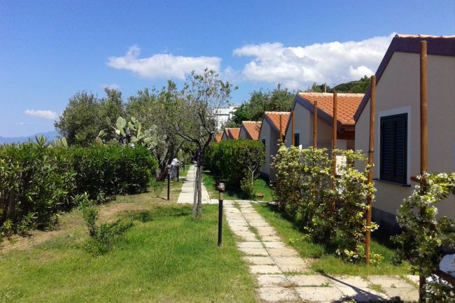 Bungalow con tetti rossi, affiancati da un vialetto lastricato e giardini curati.