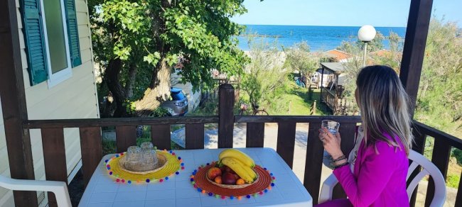 Donna con bicchiere su terrazza vista mare.