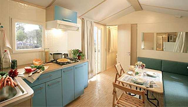 Cucina moderna con mobili blu, tavolo apparecchiato e divanetto verde.
