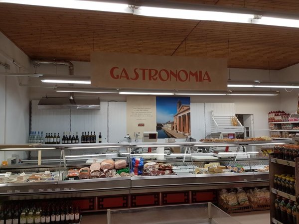 Banco gastronomia con salumi e vini esposti.