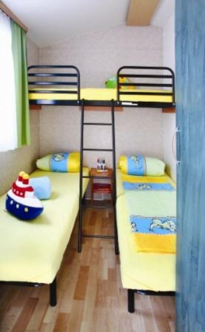 Una cameretta con due letti singoli e un letto a castello, pareti colorate e decorazioni marine.