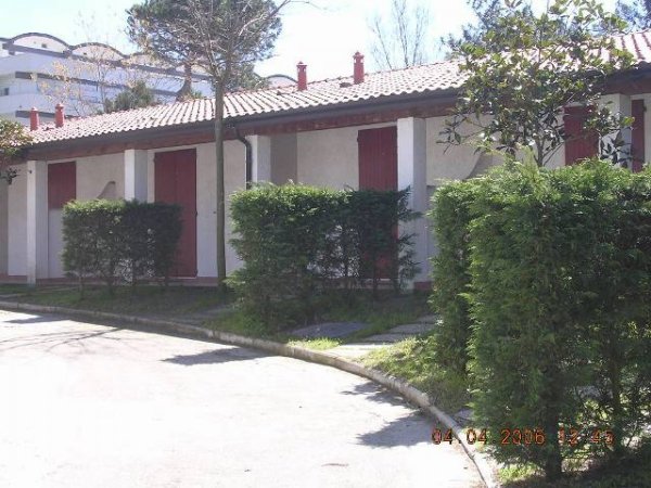 Struttura con tetto rosso e cespugli davanti.