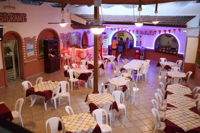 Sala ristorante con tavoli apparecchiati e sedie bianche.