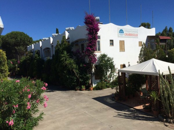 Edificio bianco con giardino e bougainvillea fiorita.