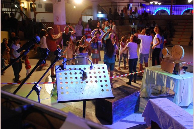 Persone danzano in un'atmosfera festosa, microfono in primo piano.
