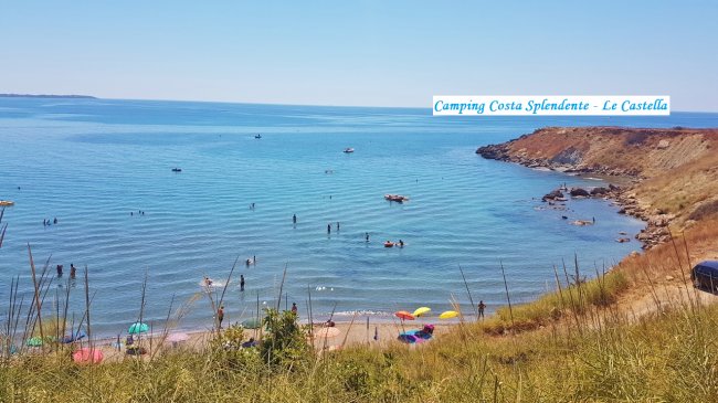 Spiaggia affollata con ombrelloni colorati e persone che nuotano nel mare.