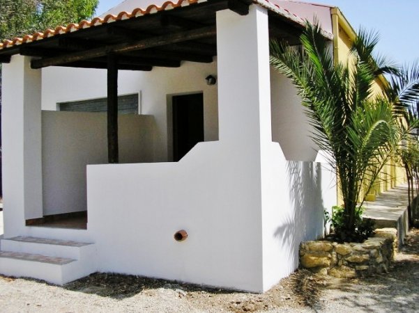 Bungalow bianco con veranda e pianta.