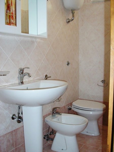 Bagno con lavabo, bidet, wc e piastrelle chiare.