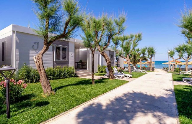 Sentiero tra villette e mare con sdraio.