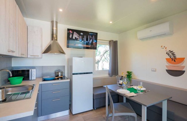 Cucina moderna con tavolo da pranzo, frigo e TV.